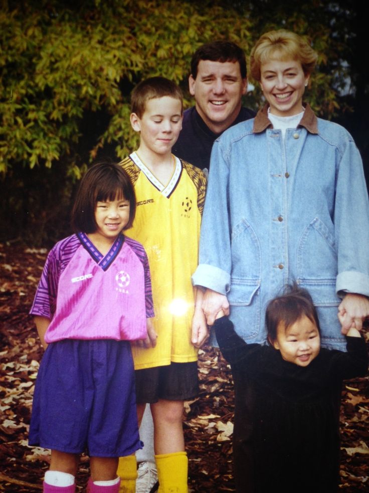 a family posing for a photo in front of some trees and leaves on the ground