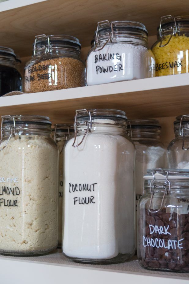 many jars with different types of food in them are labeled on the shelves, including almonds, chocolate and powder