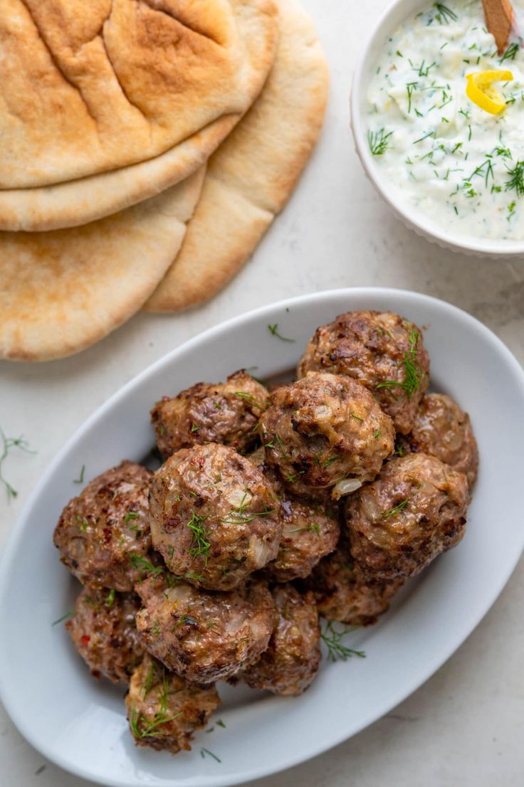 meatballs and pita bread on a white plate next to a bowl of yogurt