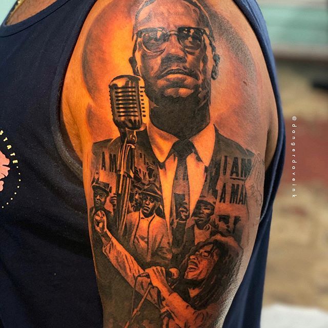 a man with a tattoo on his arm has a microphone in front of him and an image of martin luther king