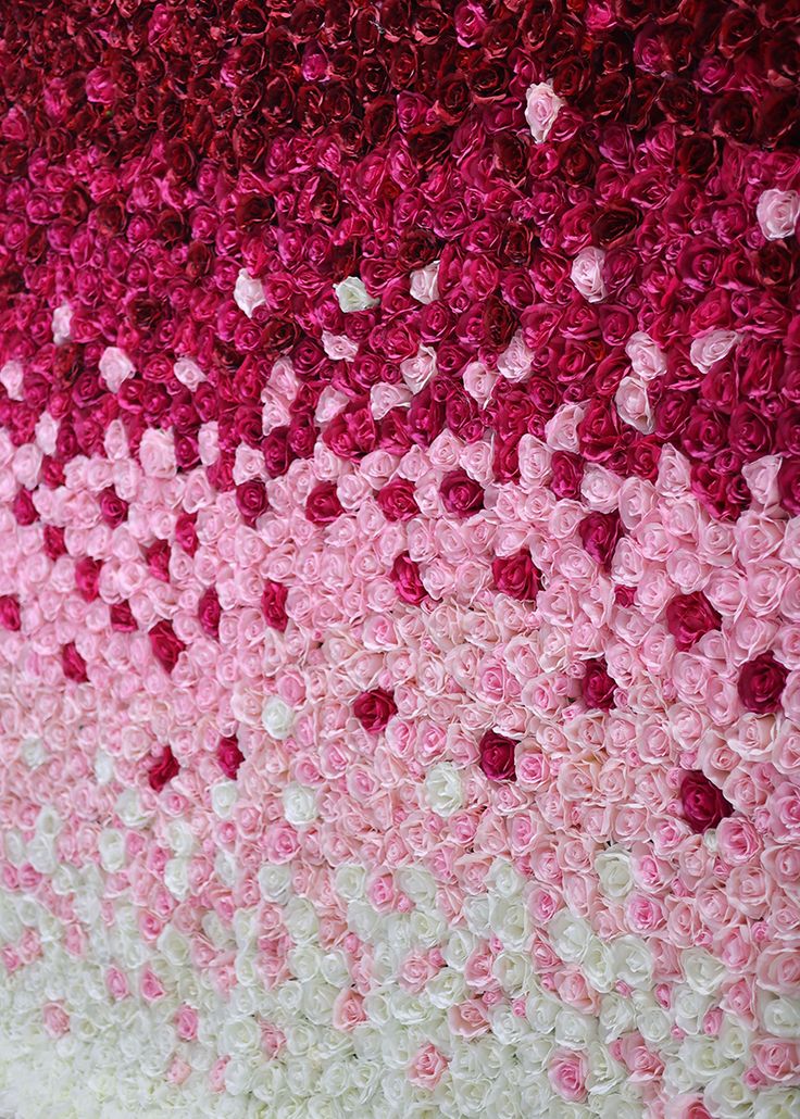 pink and white crocheted wall hanging on the side of a building with flowers in it