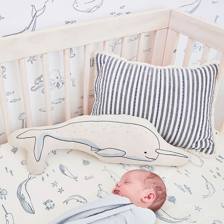 a baby is sleeping in his crib next to a pillow and stuffed toy whale