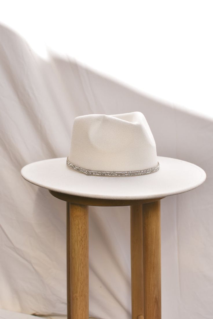 The must-have addition to your cowgirl bachelorette outfit? Add a hat! Our White Fedora with Rhinestone Band is one of those styles that goes with absolutely everything. It features a classic white fedora silhouette, adorned with a dazzling silver rhinestone band. Adjustable ties inside to give you a perfect fit. Due to high demand and shipping costs related to our hat collections, hats purchased are returnable for store credit only or exchange. Elegant White Adjustable Fedora, White Hats With Rhinestones And Curved Brim, White Rhinestone Hat With Curved Brim, White Brimmed Felt Hat For Party, White Fedora Felt Party Hat, White Fedora Felt Hat For Party, Elegant White Hat Bands For Rodeo, Elegant White Hat Band For Rodeo, White Fedora Hat For Party