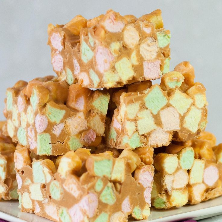 some kind of candy bar sitting on top of a white and purple plate with pink, green and yellow marshmallows