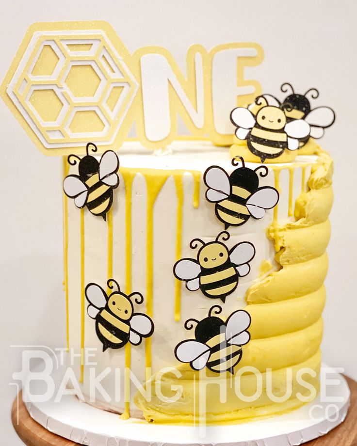 a cake decorated with bees and honeycombs on a wooden stand in front of a white wall