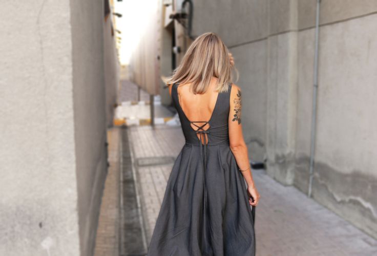 a woman walking down the street with her back to the camera, wearing a black dress