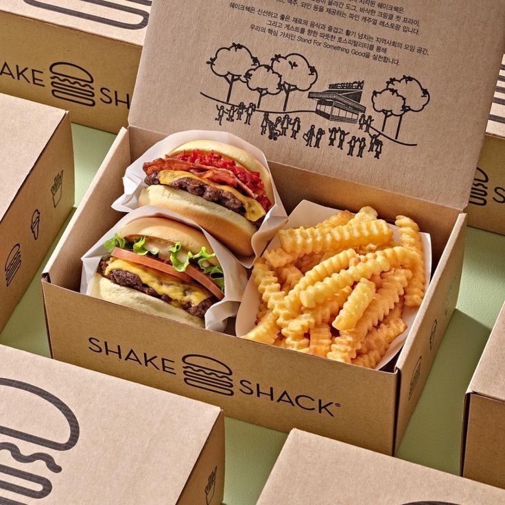 several boxes filled with sandwiches and french fries on top of green tableclothed flooring