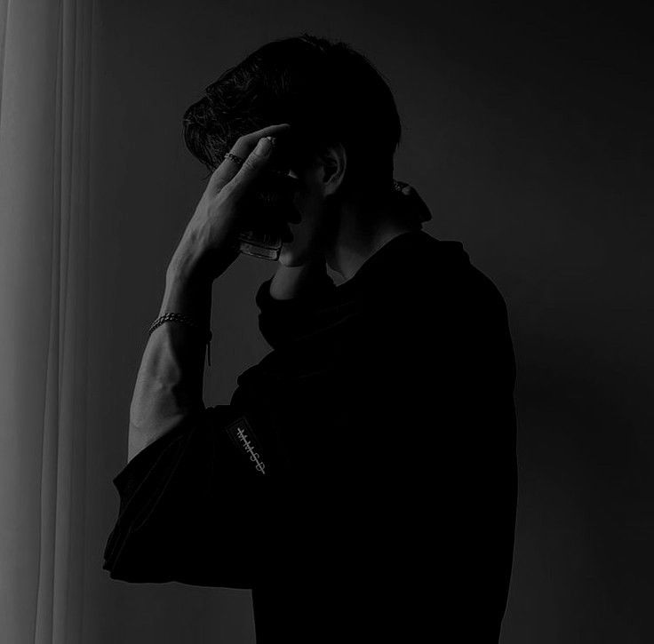 a man standing in front of a window talking on a cell phone while holding his head to his ear