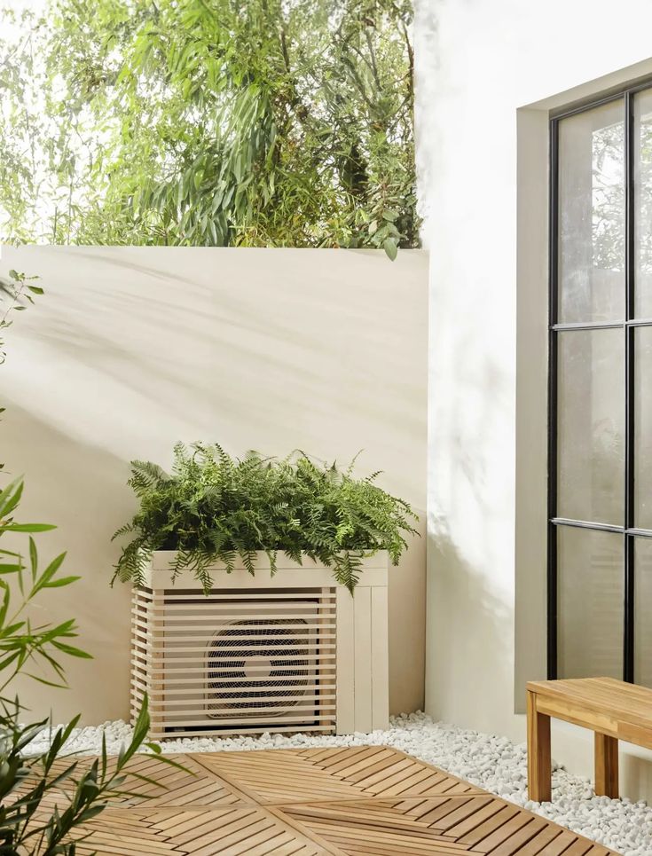 an air conditioner sitting on top of a wooden floor next to a plant in a pot