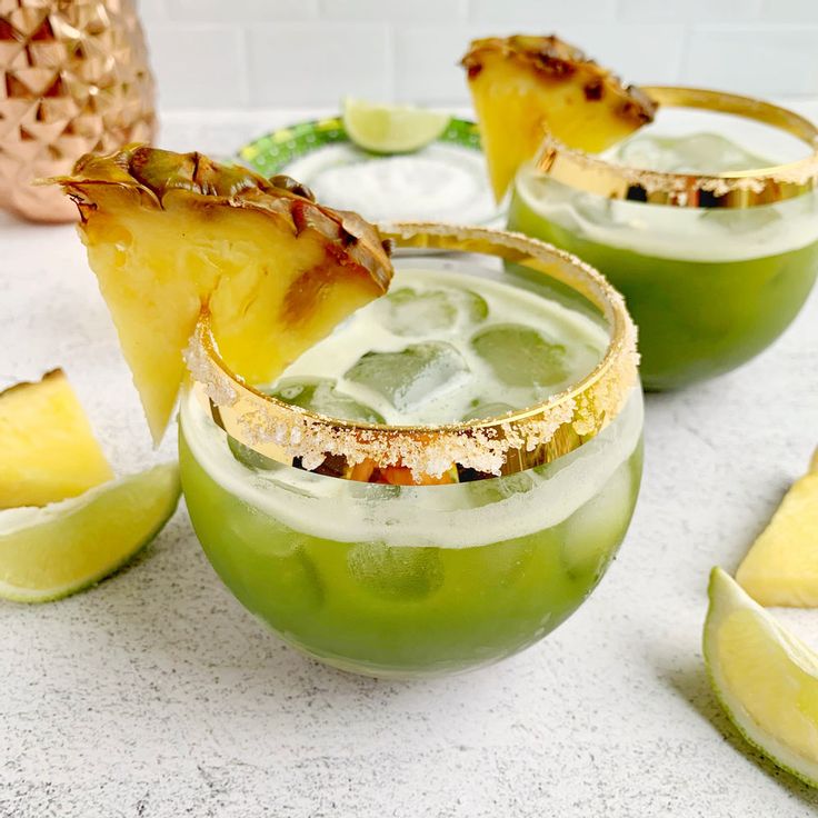 two margaritas with pineapple garnish on the rim