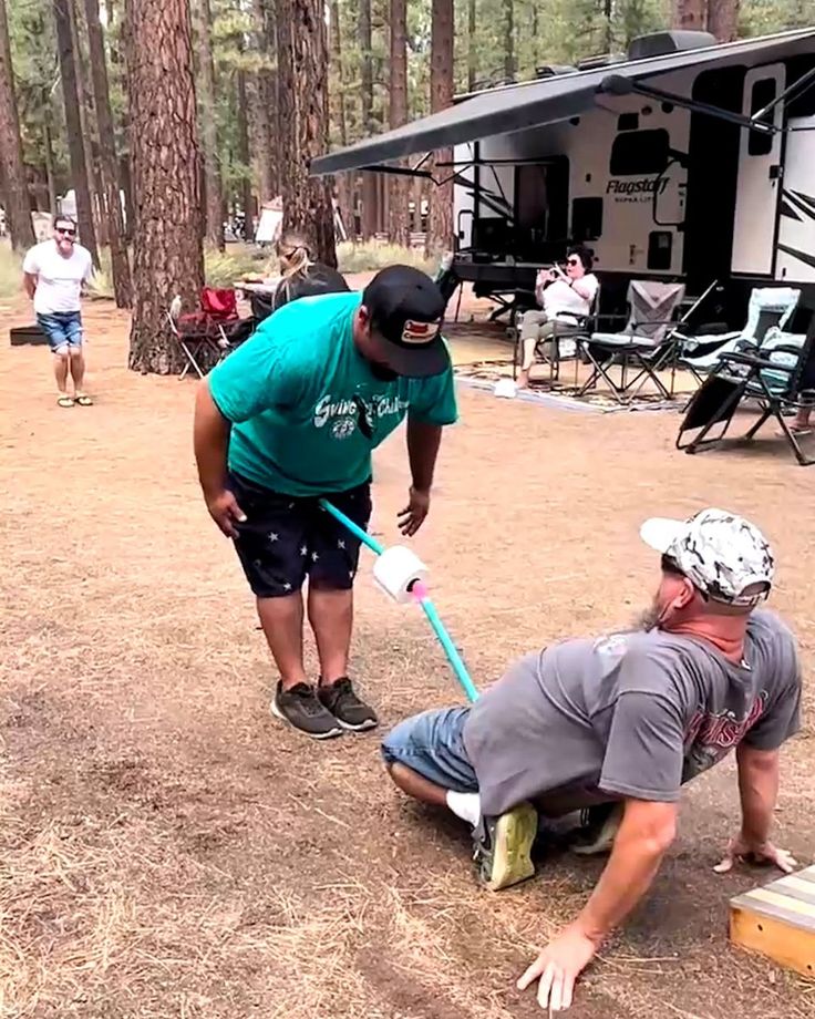 two men are in the woods playing with a baseball bat and another man is on the ground