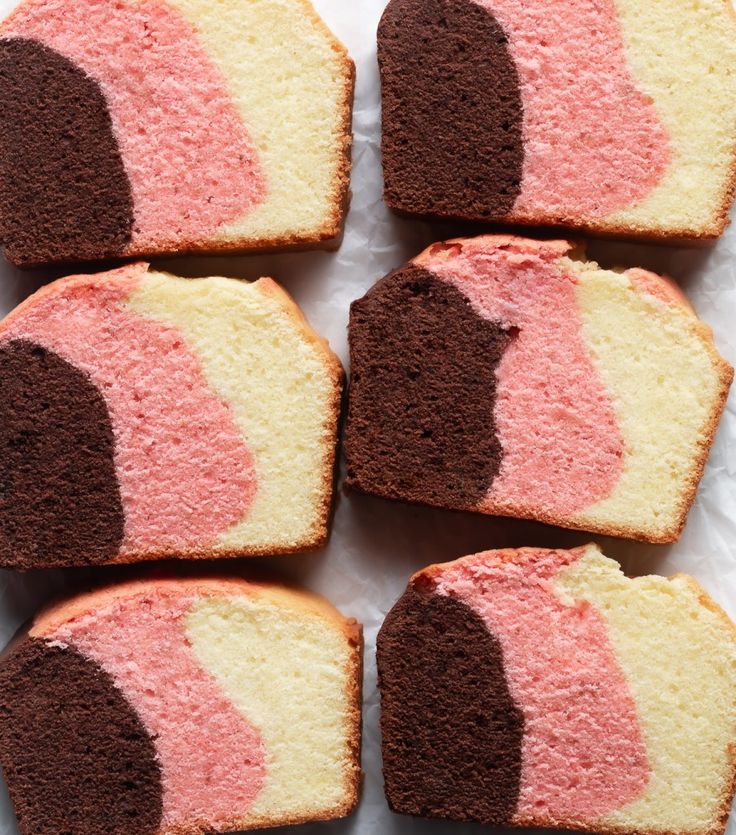 several pieces of cake with pink and brown frosting on them sitting on a white surface