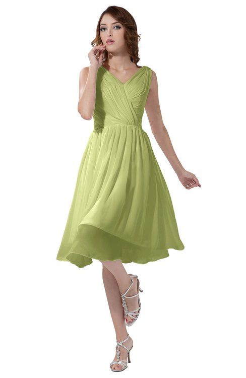 a woman in a green dress is talking on her cell phone and posing for the camera