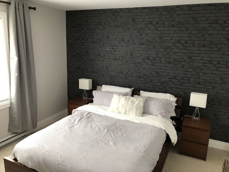 a bedroom with a brick wall behind the bed and two lamps on either side of the bed