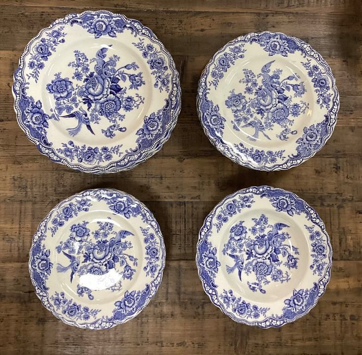 four blue and white plates sitting on top of a wooden table