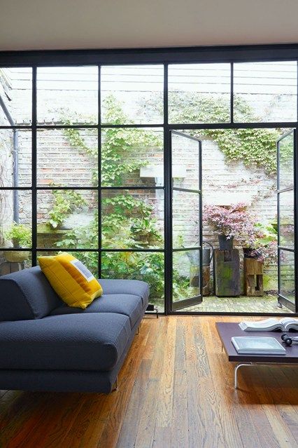 a living room filled with furniture and lots of glass doors that open up to the outside