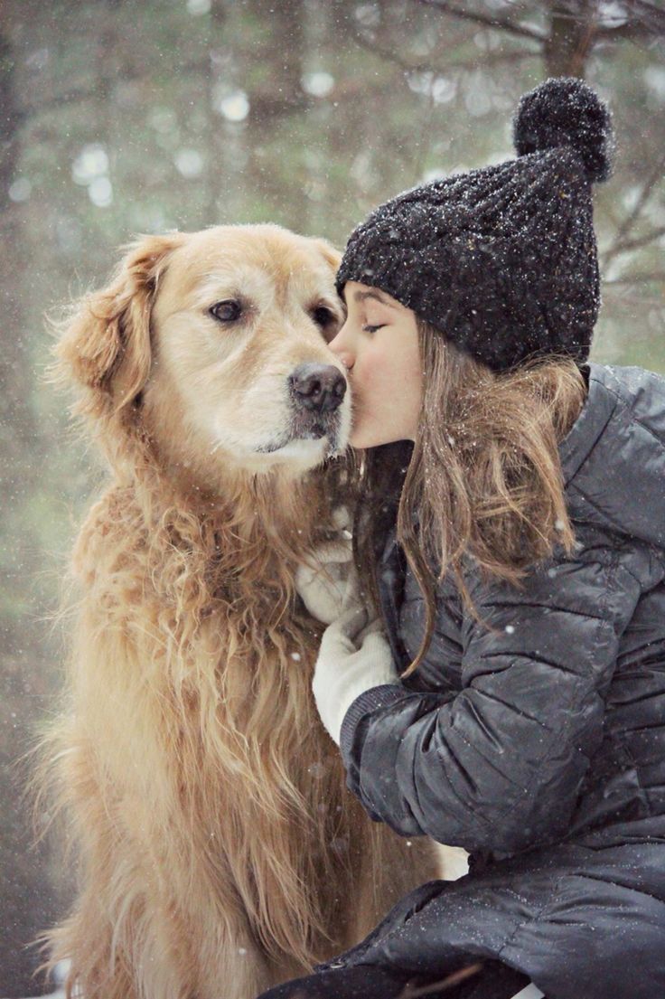 a woman kissing her dog in the snow