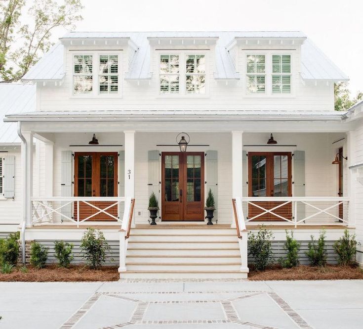 a white house with red front doors and steps leading up to the front door is shown