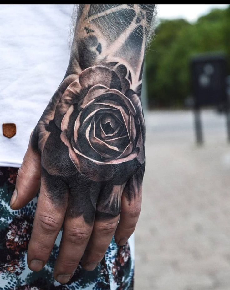 a man's hand with a black rose tattoo on it and his left hand