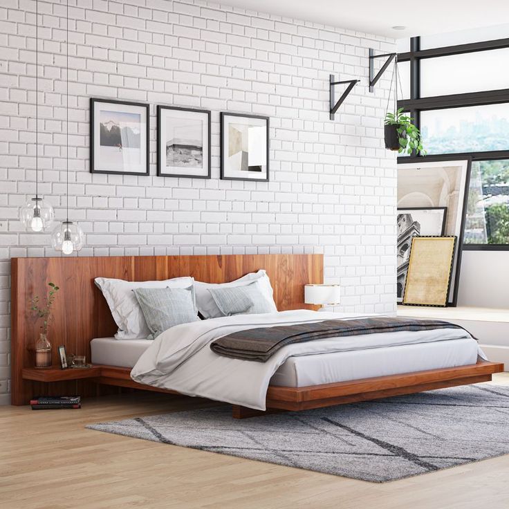 a bedroom with white brick walls and wooden bed frames on the wall, along with an area rug