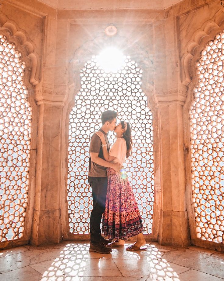 a man and woman standing in front of a window with sunlight coming through the windows