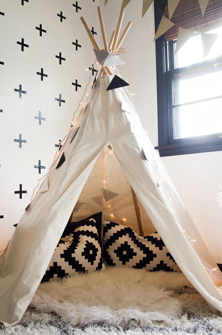 a teepee tent with pillows and lights in the corner