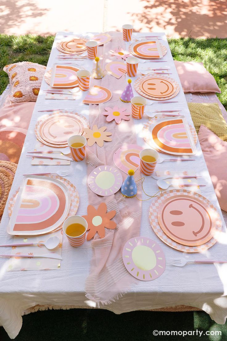 a table set up with plates, cups and napkins in the shape of flowers