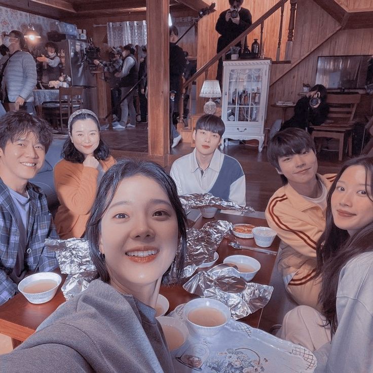 a group of people sitting at a table with food and drinks in front of them