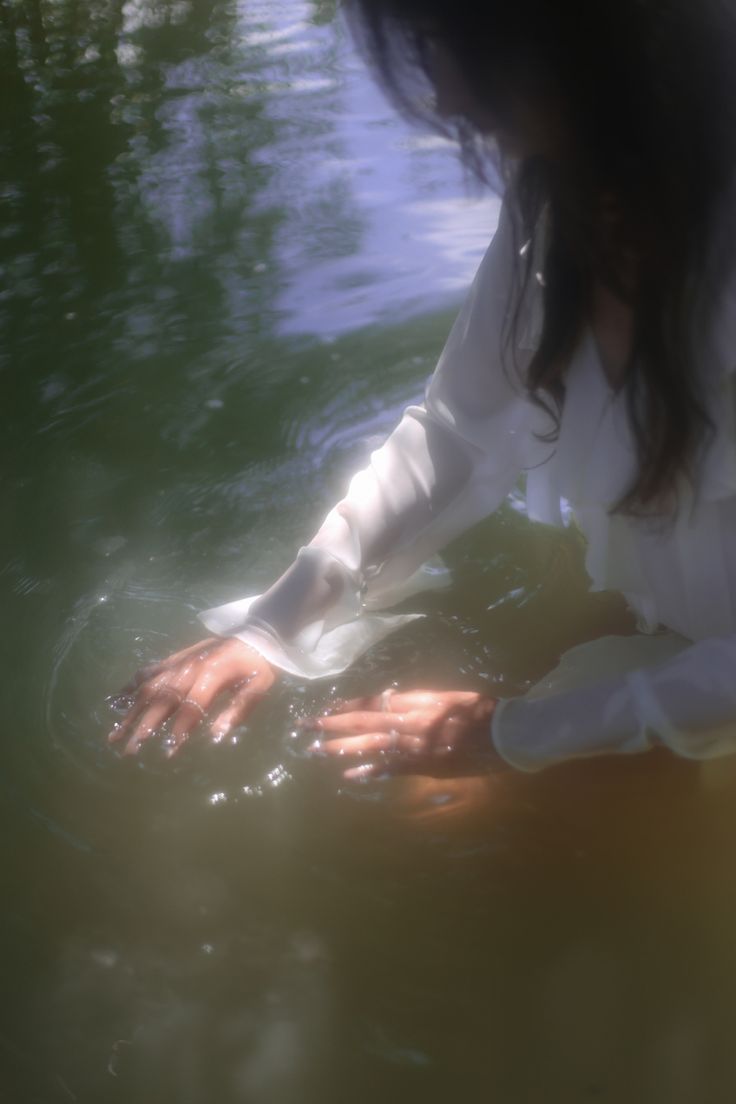 a woman sitting in the water with her hand on top of something that is floating