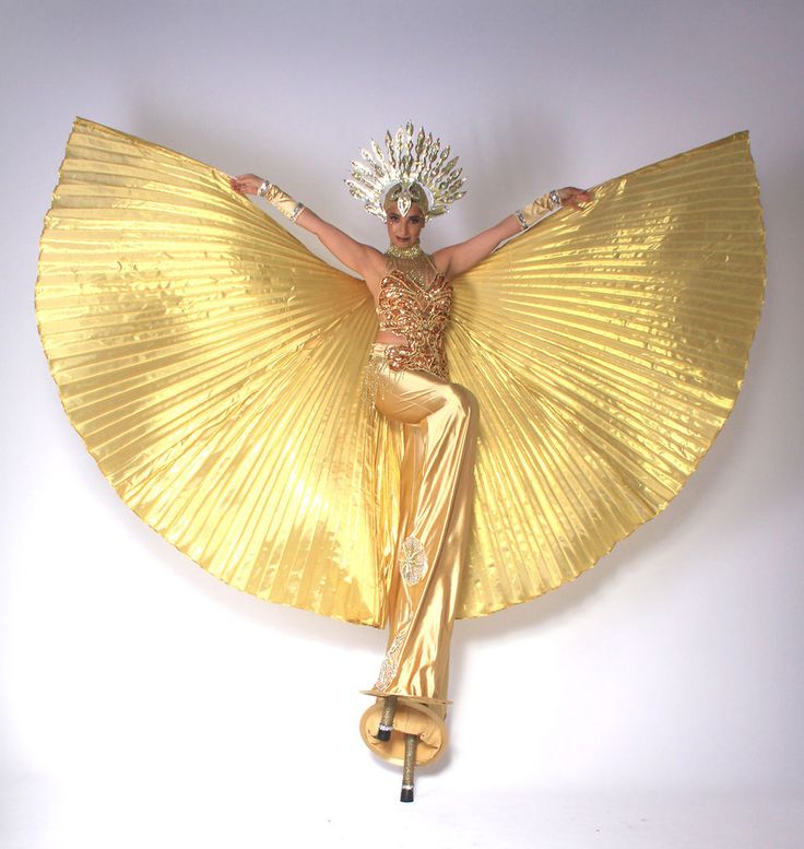 a woman is dressed in gold and holding her arms out while standing on one leg