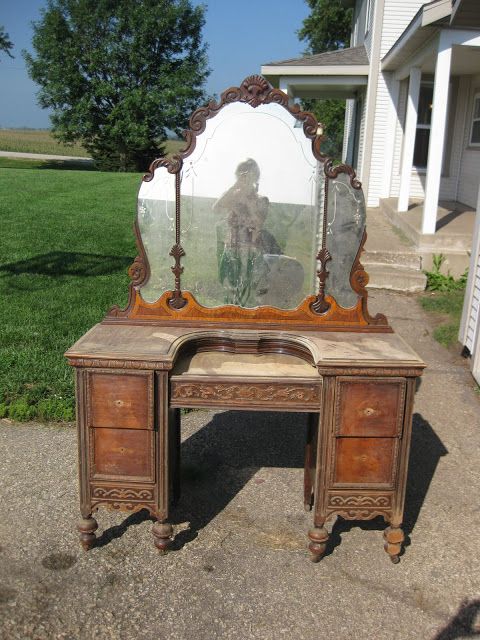 an old desk with a mirror on it in front of a white house and grass