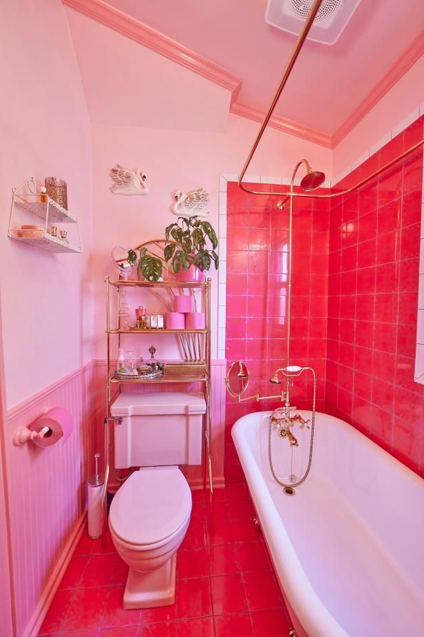 a pink bathroom with a toilet, bathtub and shelf filled with plants in it