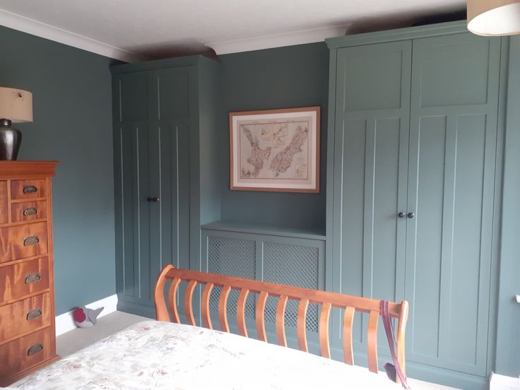 an image of a bedroom setting with blue walls and green cupboards on the wall