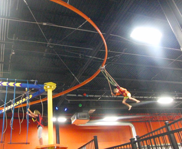 a person is doing tricks on a trampoline in an indoor area with lights