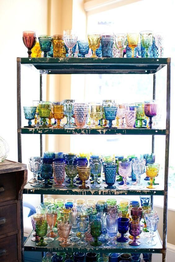 several shelves filled with different colored glass cups