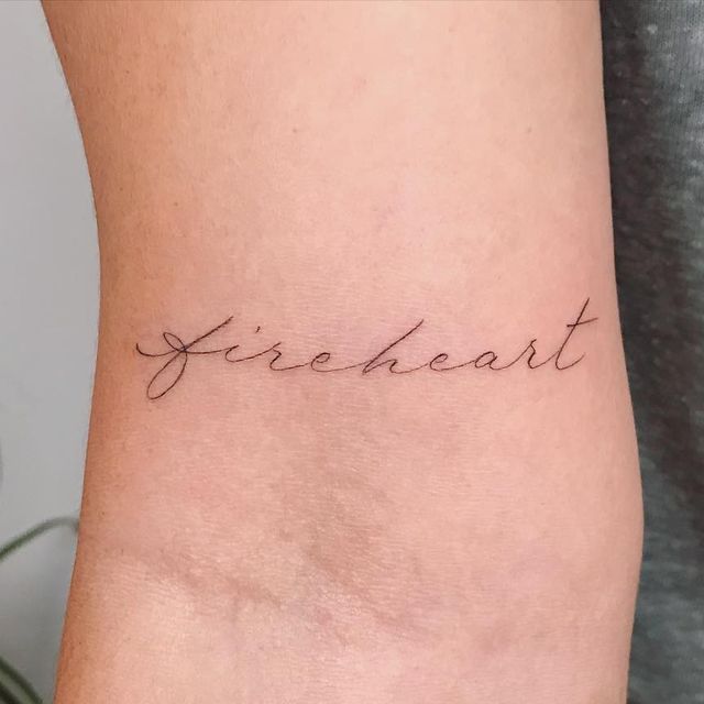 a woman's arm with the word fire heart tattooed on her left side ribcage