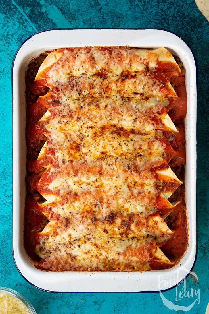 a casserole dish with meat and cheese in it on a blue tablecloth