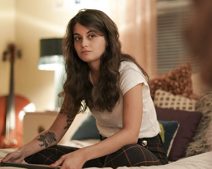 a woman sitting on top of a bed holding a laptop computer