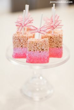 an image of desserts on a cake plate with candy sticks in the middle and pink marshmallows at the bottom