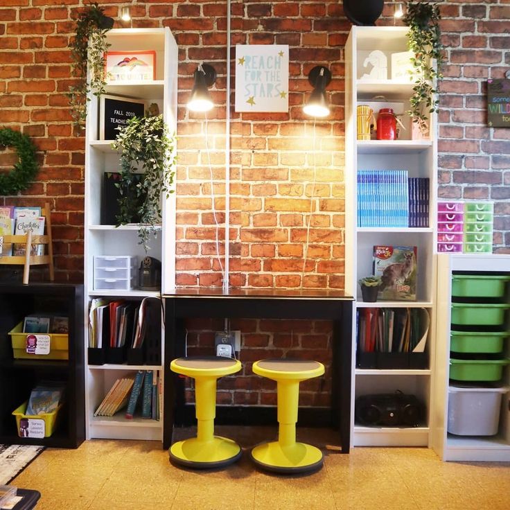 two yellow stools sitting in front of a book shelf filled with books and plants