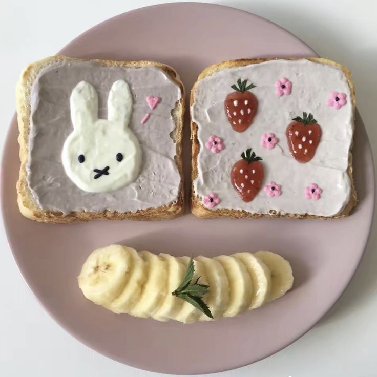 two slices of bread with white frosting and strawberries on them, one is shaped like a rabbit