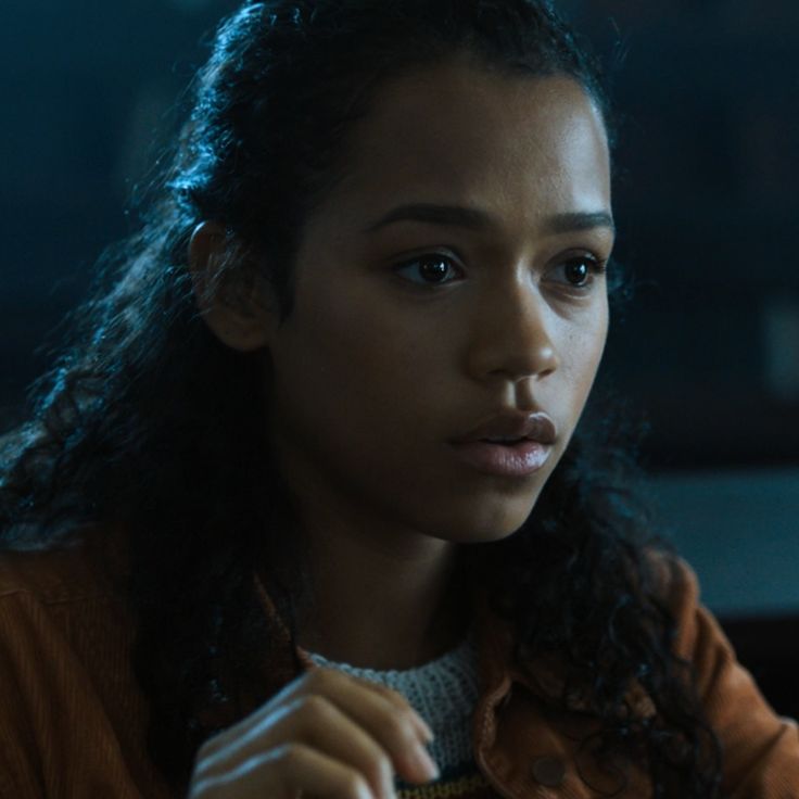 a young woman sitting at a table in front of a laptop computer and looking off to the side