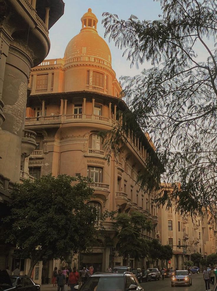 cars are parked on the street in front of an old building with a domed dome