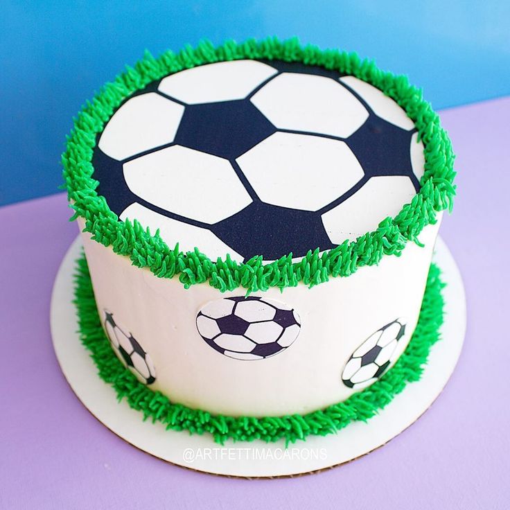 a soccer themed cake with green icing on a purple tablecloth and blue background