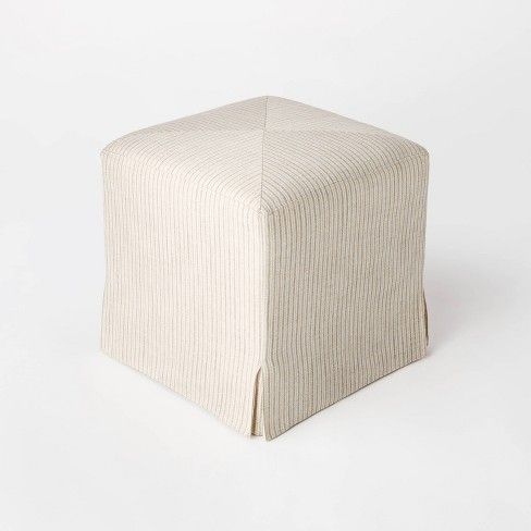 a white square ottoman sitting on top of a floor