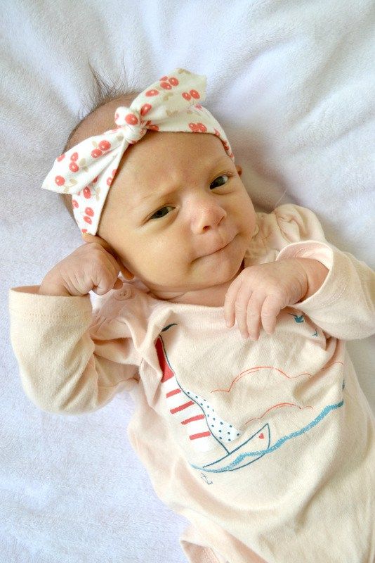 a baby laying on top of a bed wearing a headband