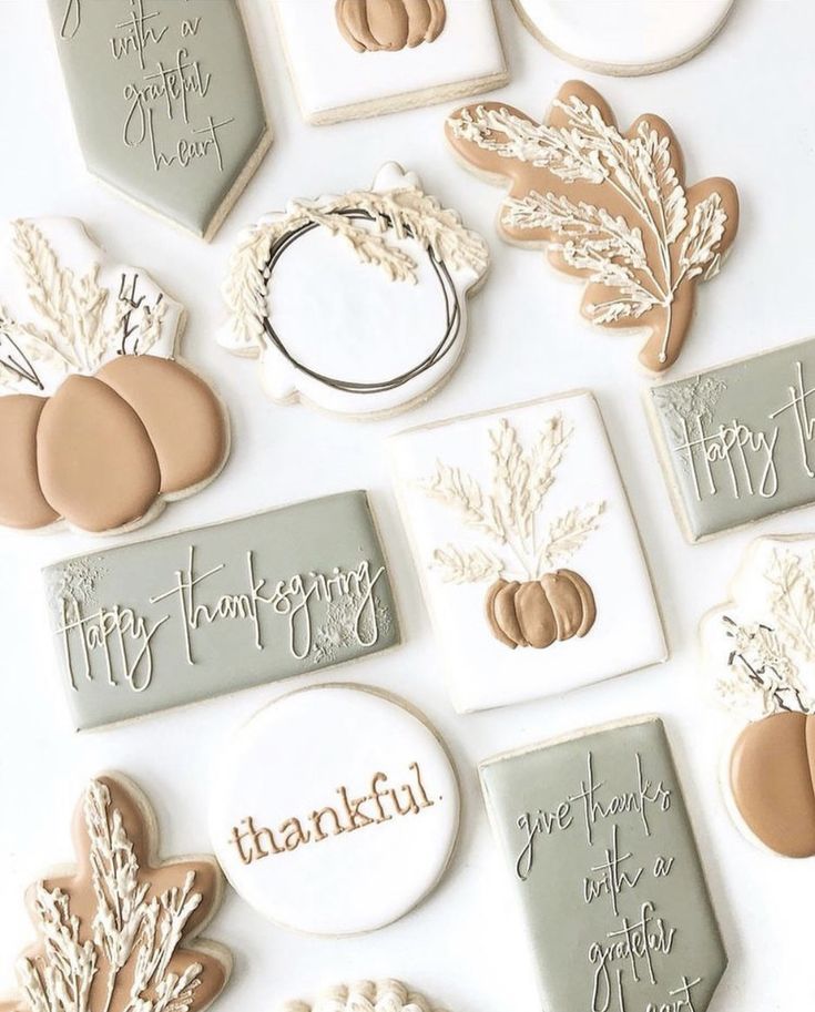 cookies decorated with thanksgiving sayings and pumpkins are arranged on a white table top