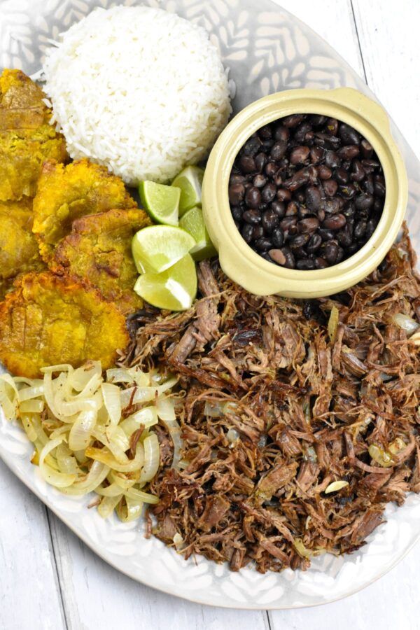 a white plate topped with meat, rice and beans