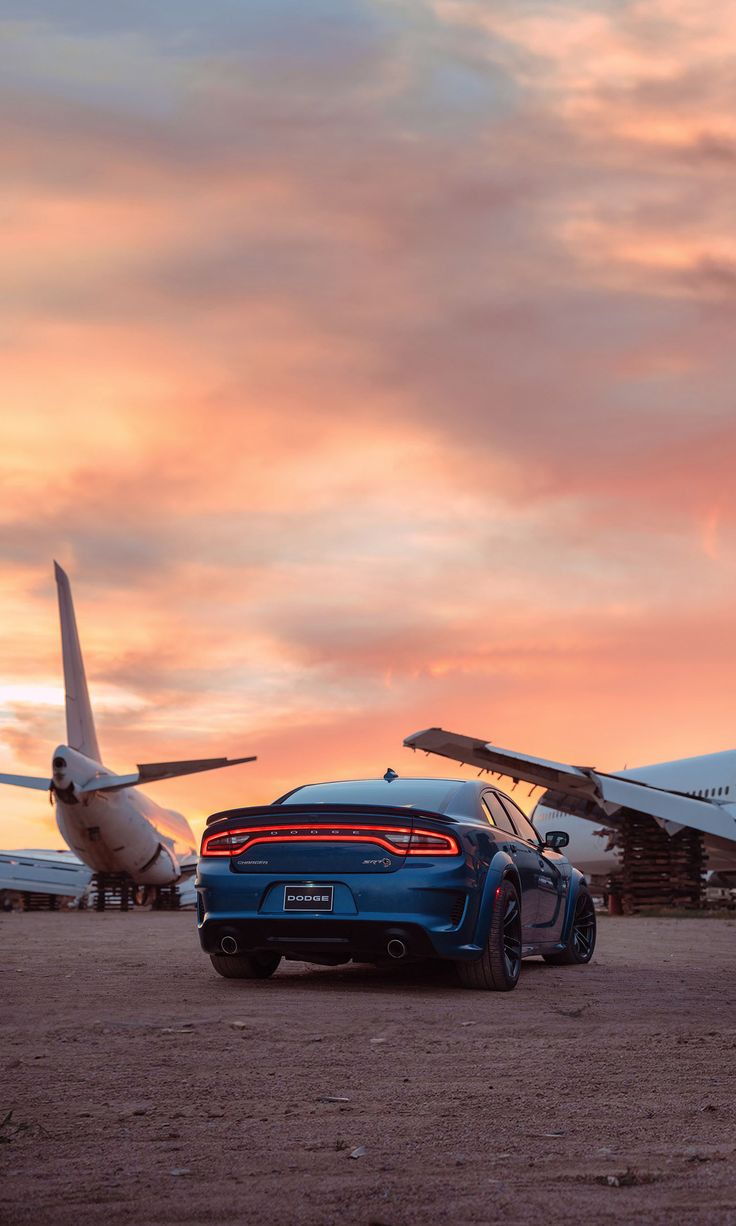 a blue sports car parked next to an airplane