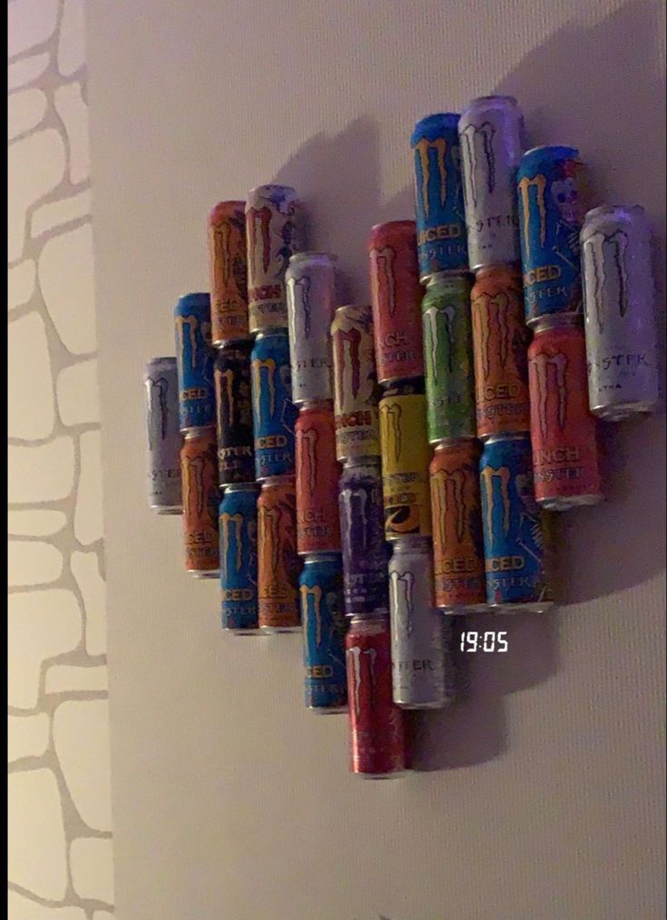 there are many cans on the wall and one is made out of soda cans in different colors